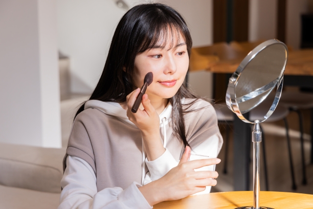 堺市の葬儀に参列する女性が、フェイスパウダーを使って艶を抑えたマットな仕上がりでメイクを整えている様子をイメージした画像